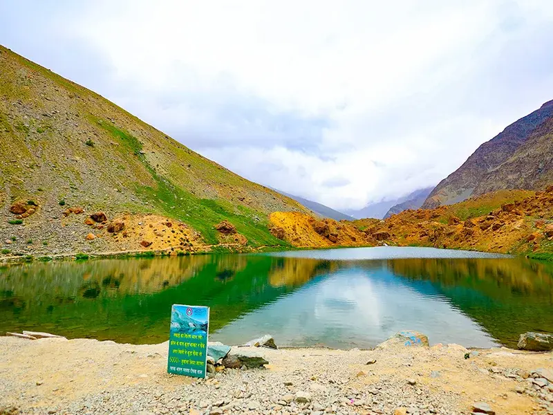 Crystal-clear Deepak Tal lake surrounded by Himalayan mountains